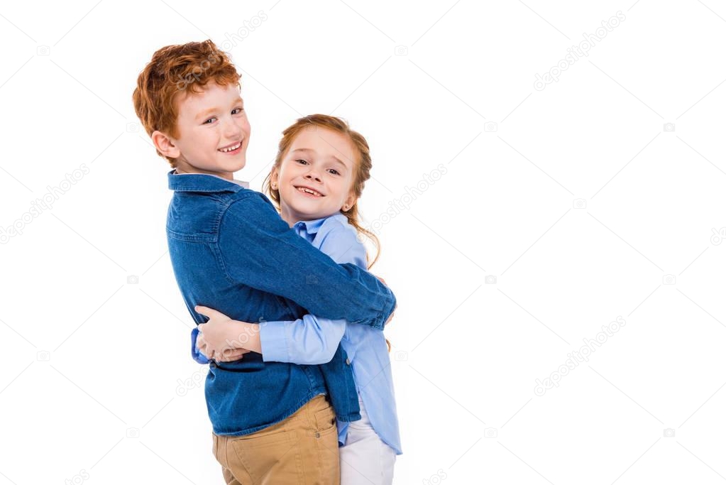 adorable redhead children hugging and smiling at camera isolated on white