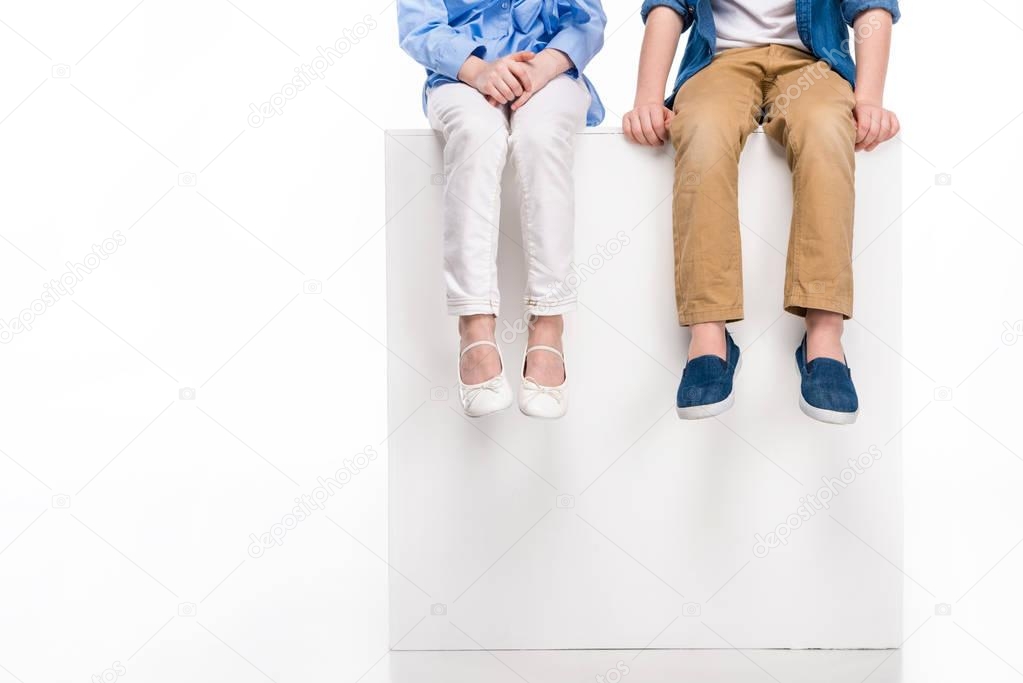 cropped shot of children sitting on white cube isolated on white