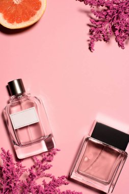 şişe parfüm pembe çiçekler ve turuncu ile üstten görünüm pembe yüzeyi