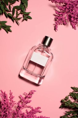 çiçek ve yaprakları pembe yüzeyi ile parfüm şişe, üstten görünüm