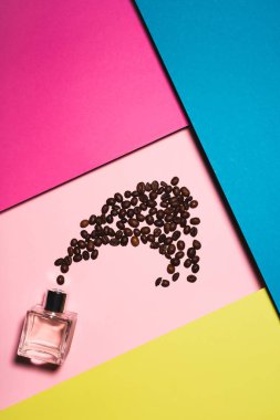 top view of bottle of perfume with coffee beans on colorful surface clipart
