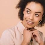 Retrato de cerca de la mujer afroamericana feliz aislado en beige