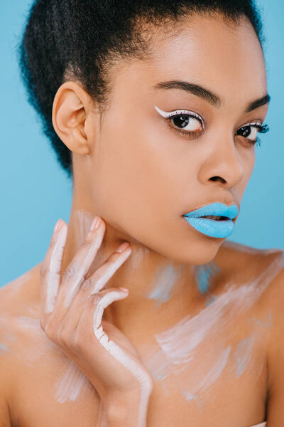 young african american woman with creative makeup and perfect skin looking at camera isolated on blue