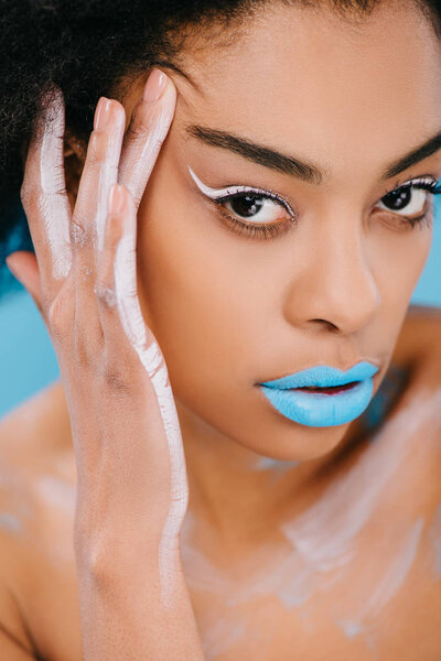 close-up portrait of sensual young woman with creative makeup and blue lips on blue