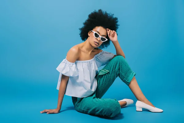 Aantrekkelijke Jonge Vrouw Stijlvolle Shoulder Top Zonnebril Zittend Vloer Blauw — Stockfoto