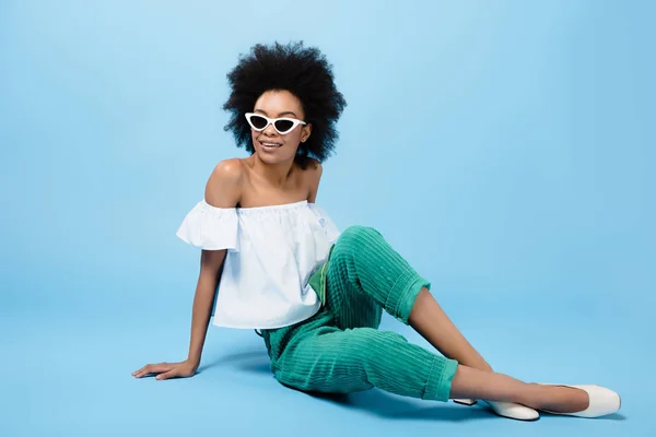 Young African American Woman Stylish Clothes Sunglasses Sitting Floor Blue — Stock Photo, Image