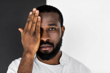 yakışıklı şık Afrikalı-Amerikalı adam göz el ile kapatma ve kameraya bakarak Beyaz giysili