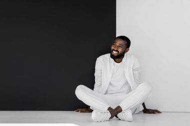 siyah ve beyaz duvarının yakınında katta oturan şık Afrikalı-Amerikalı adam gülümseyen