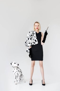attractive stylish blonde woman in black dress holding cigarette, dalmatian dog on floor