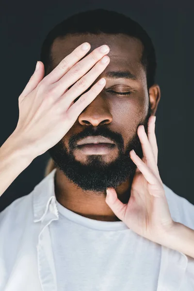 cropped image of girlfriend closing african american boyfriend eyes isolated on black