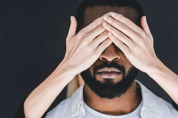 обрезанное изображение подружки закрывающей глаза африканского бойфренда, изолированные на черном
