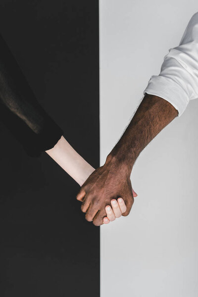 cropped image of multicultural couple holding hands, yin yang concept