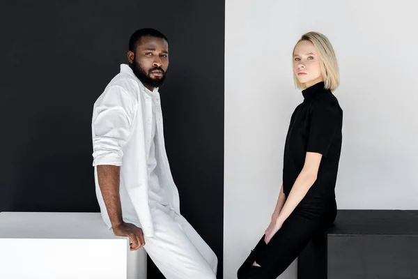 Side View Multicultural Couple Sitting Black White Cubes — Stock Photo, Image