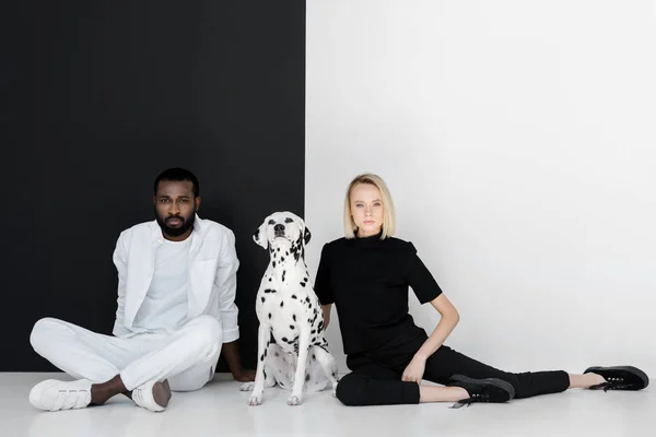 Multiculturele Paar Zitten Buurt Van Zwarte Witte Muur Met Dalmatische — Stockfoto