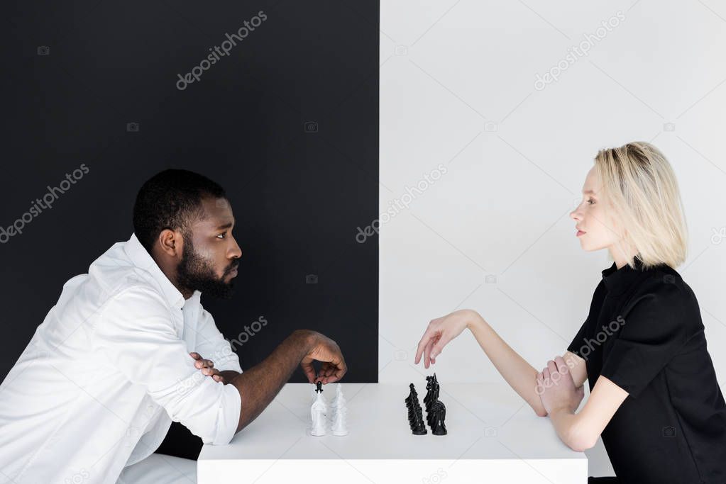 side view of african american boyfriend and blonde girlfriend playing chess