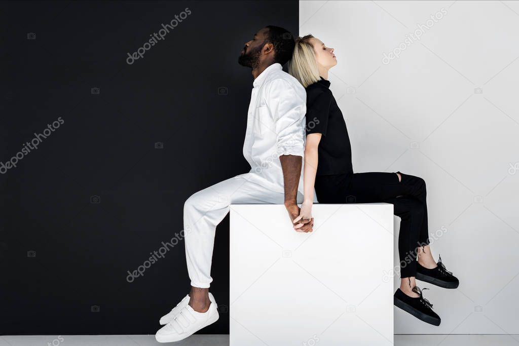 multicultural couple holding hands on white cube, yin yang concept