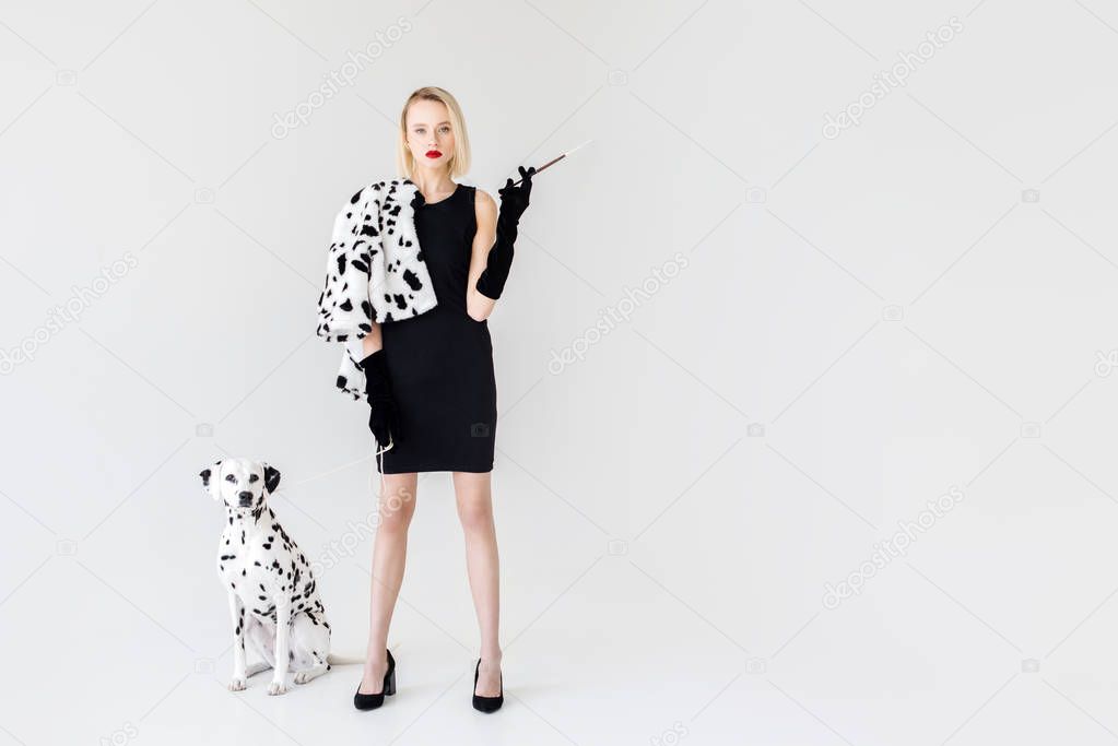 attractive stylish blonde woman in black dress with dalmatian dog on white