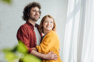 seçici odak mutlu genç çiftin sarılma ve uzakta ev arıyorum 