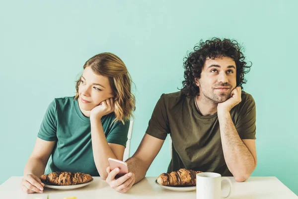 Sonriente Pareja Usando Smartphone Mirando Hacia Otro Lado Mientras Desayunan —  Fotos de Stock