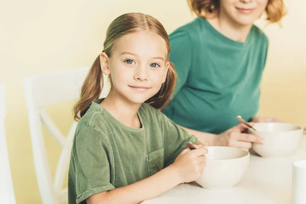 一緒に朝食を食べるかわいい小さな娘と母のショットをトリミング  — 無料ストックフォト