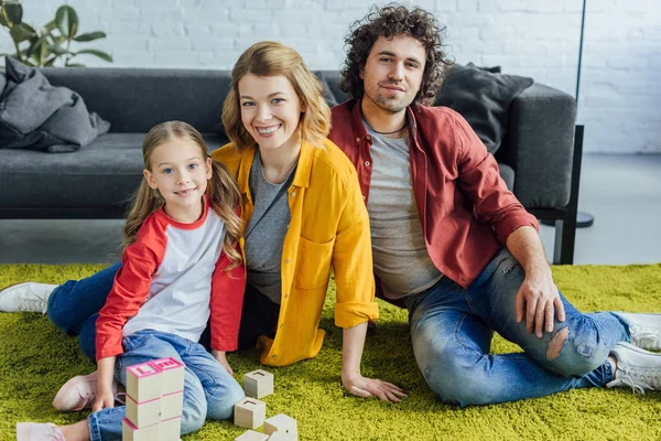 Famiglia Felice Seduta Sul Tappeto Sorridente Alla Macchina Fotografica Mentre — Foto Stock