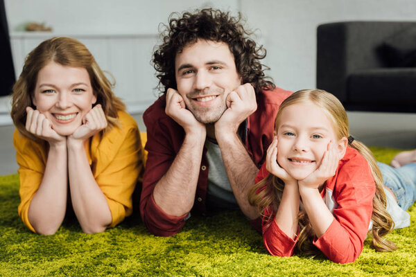 happy family with one child lying together and smiling at camera