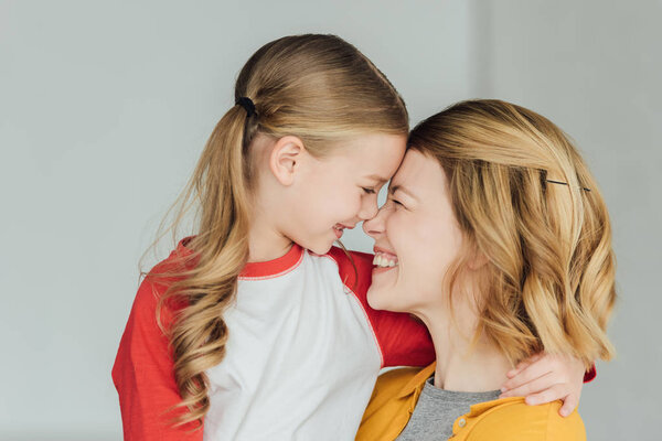 счастливая мать и дочь обнимаются и улыбаются дома
