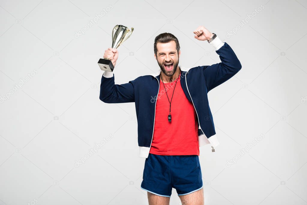 excited sportive coach screaming and holding trophy cup, isolated on white