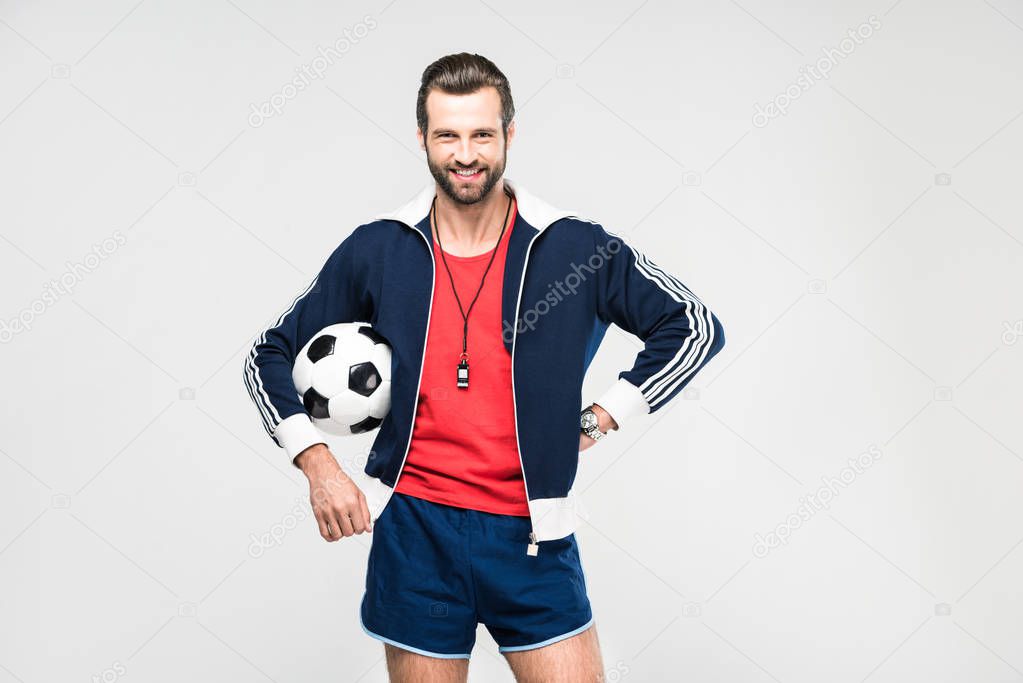 cheerful soccer coach with whistle and ball, isolated on white