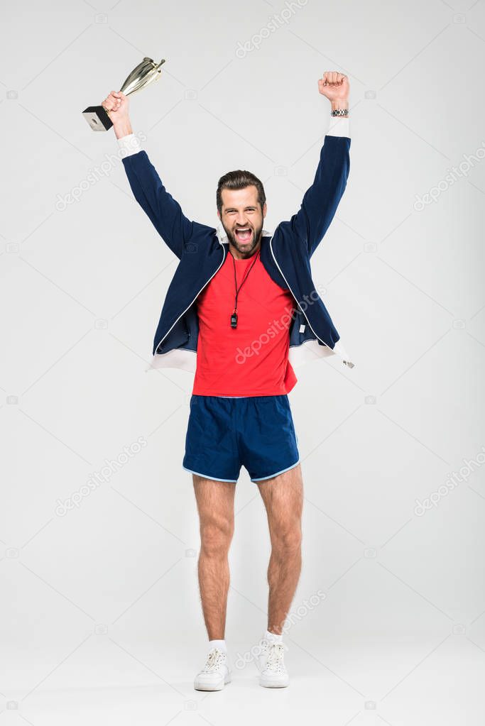 excited sportive coach with trophy cup, isolated on white