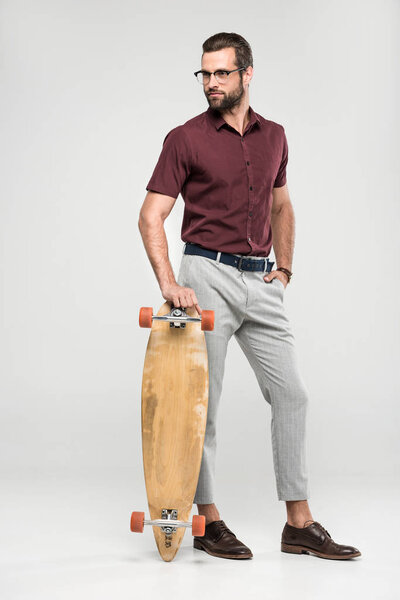 fashionable skater posing with longboard, isolated on grey