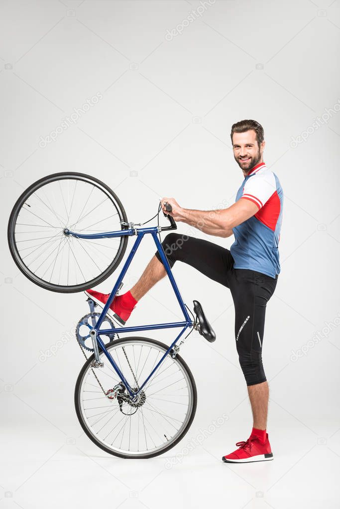 handsome smiling sportsman posing with bicycle, isolated on white