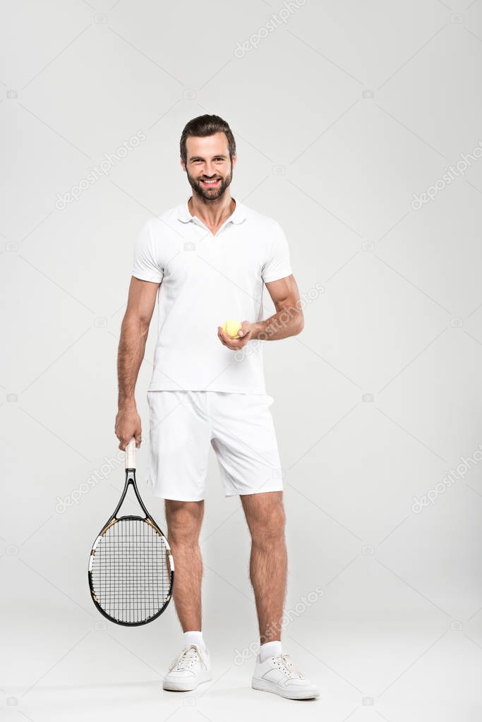 smiling tennis player with ball and racket, isolated on grey