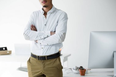 Kendine güvenen genç Afro-Amerikalı işadamı Office çapraz kollar ile ayakta kırpılmış atış