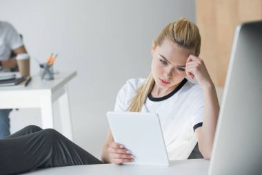 Dijital tablet işyerinde kullanma sarışın genç kadın odaklı