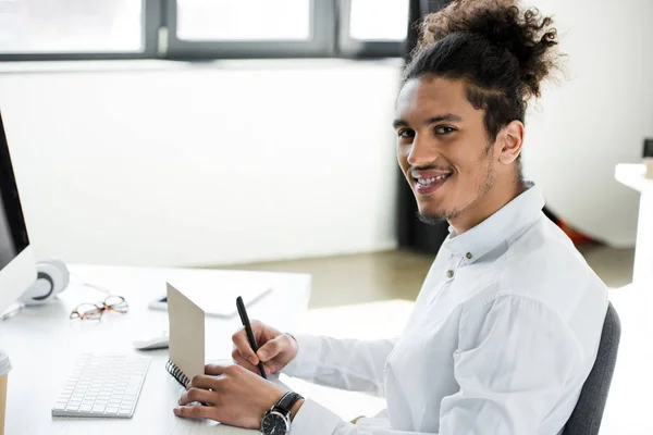 Guapo Joven Afroamericano Hombre Negocios Sonriendo Cámara Mientras Toma Notas — Foto de stock gratuita