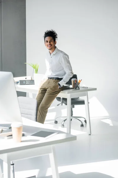 ハンサムな若いアフリカ系アメリカ人実業家のテーブルに座って オフィスでカメラで笑顔 — ストック写真