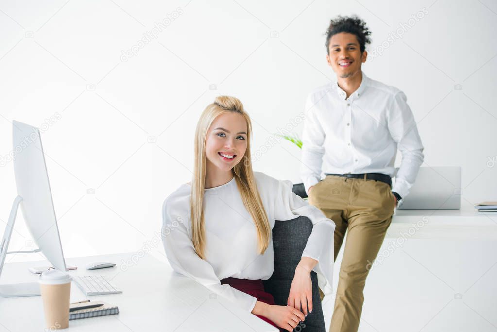 cheerful young multiethnic business people smiling at camera while working together in office