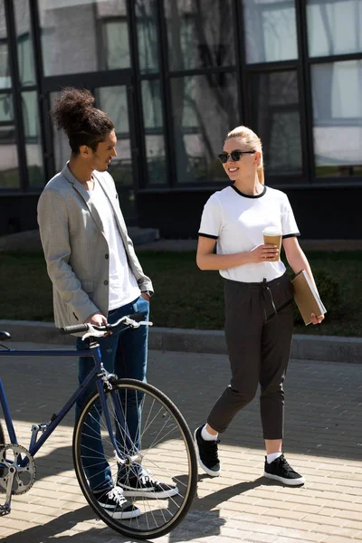 Joven Pareja Multiétnica Con Bicicleta Café Para Llevar Cuaderno Caminando — Foto de Stock
