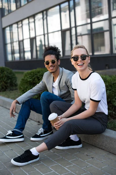 Cheerful Young Multiethnic Couple Sunglasses Smiling Camera While Drinking Coffee — Stock Photo, Image