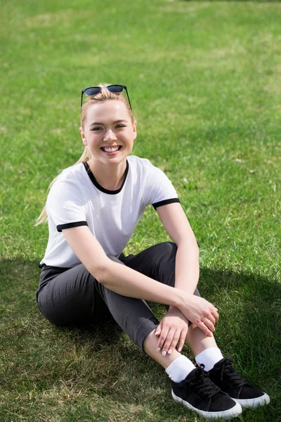 Beautiful Young Blonde Woman Sitting Green Grass Smiling Camera — Free Stock Photo