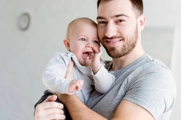 家で小さな男の子を抱えて若い笑顔の父 — ストック写真