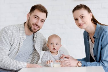 Anne ile küçük oğlu bebek şişe ile mutfak oturan gülümseyen