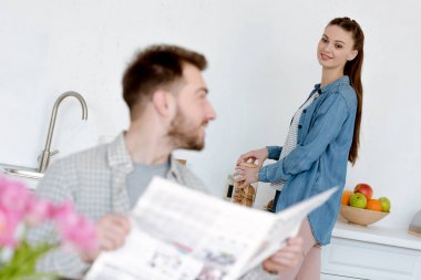 gülümseyen kadın koca gazete ile ön plan üzerinde seyir mutfak üzerinde