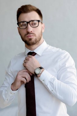 Kendine güvenen işadamı kravat ve beyaz duvara yakın poz gözlük