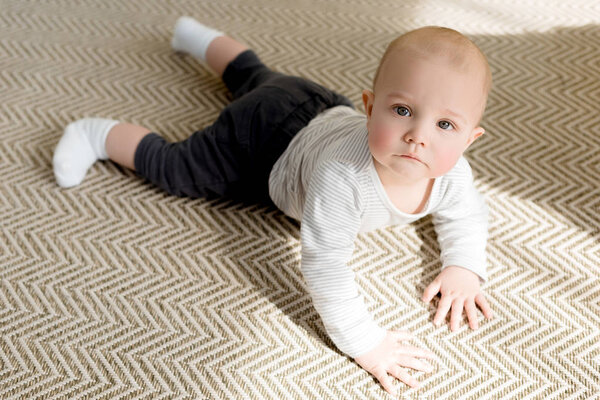 adorable little baby boy on floor looking at camera