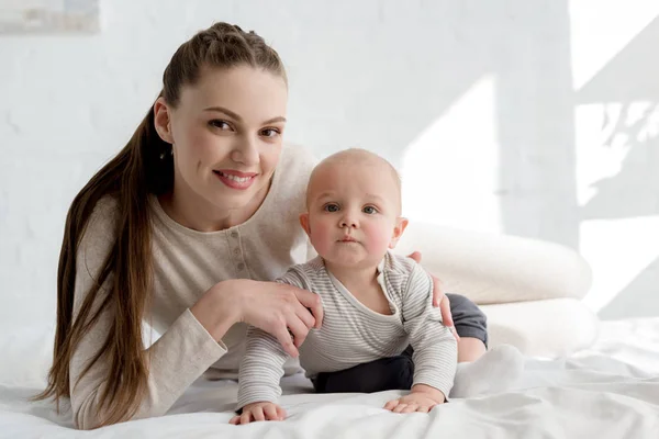 ベッドに横になっている男の子の赤ちゃんと母親を笑顔 — ストック写真