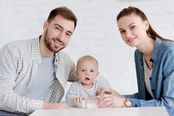 Pais Sorridentes Com Filho Pequeno Sentado Cozinha Com Mamadeira — Fotografia de Stock