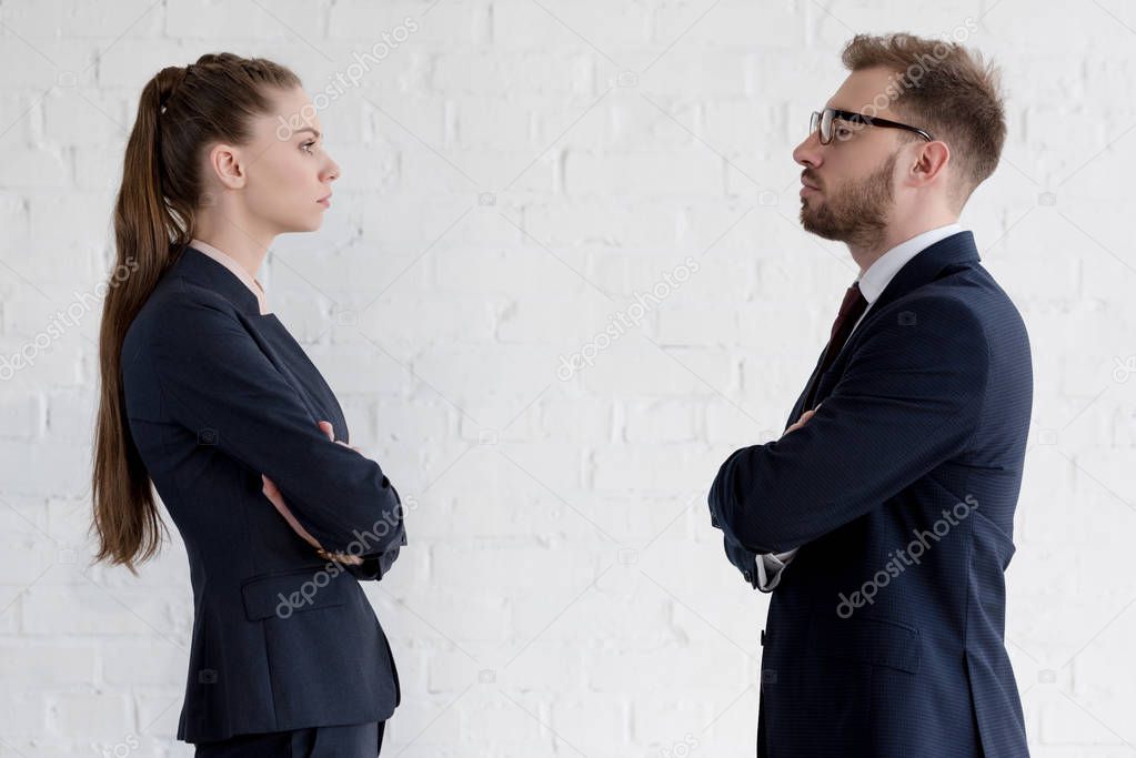 serious businesspeople with crossed arms looking at each other