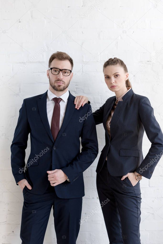 confident businesspeople posing together near white wall